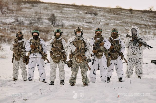 Військові у зимовому маскувальному одязі стоять посеред засніженого поля Військові у зимовому маскувальному одязі стоять посеред засніженого поля